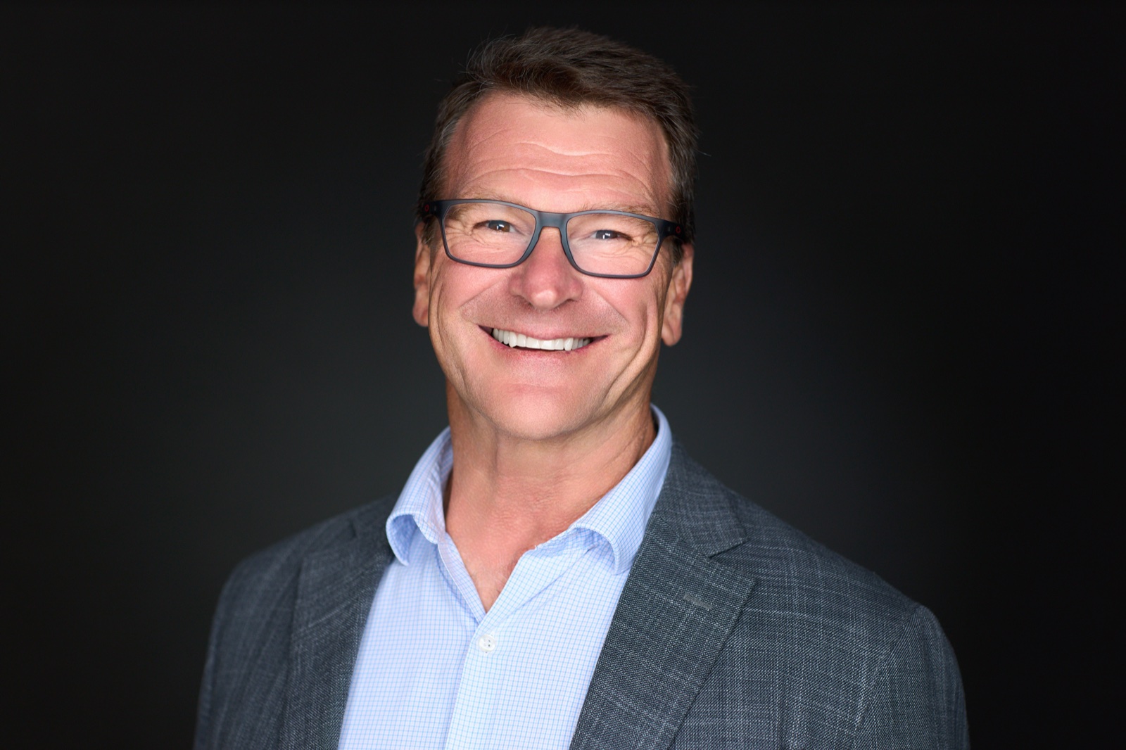 Corporate headshot with glasses on a dark studio background in Sydney